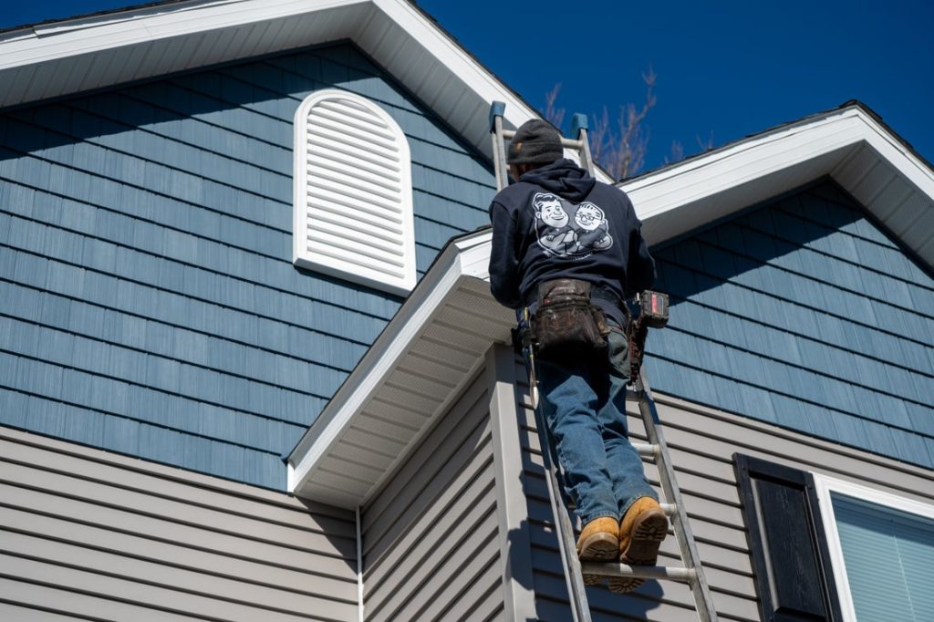 Installer climbing to a gable on a two story Hudson Valley home