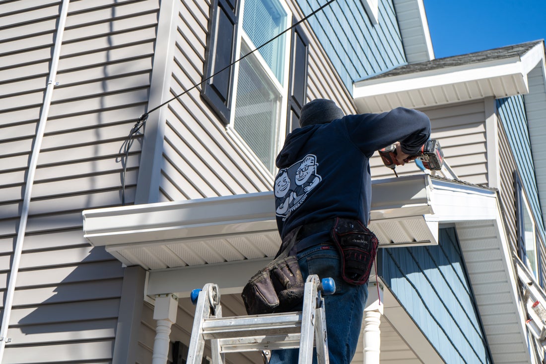 Installer hanging a gutter over a front entry