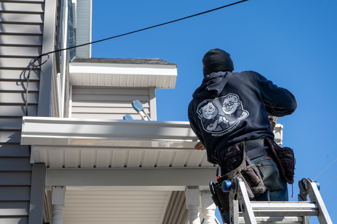 Installer securing a gutter above a porch roof
