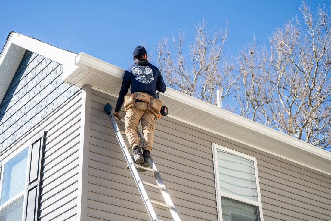Hudson Valley installer on a ladder running a new gutter along the roofline